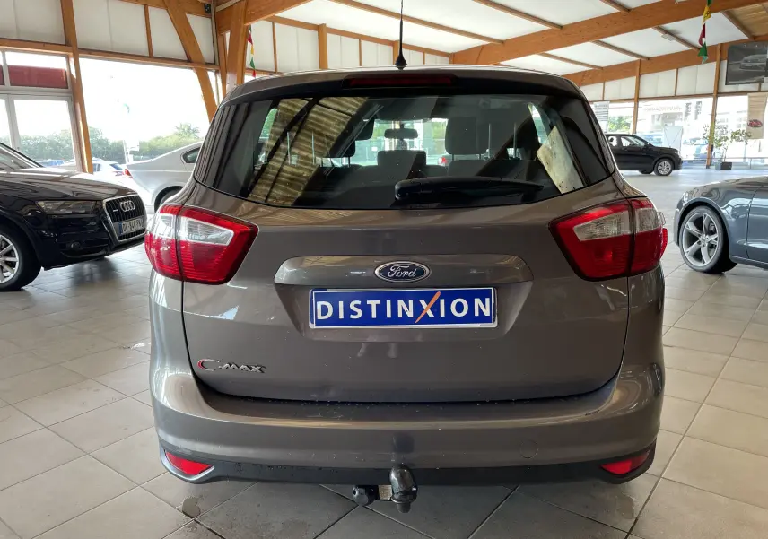 Vue arrière d'un Ford C-MAX gris 2012 avec attelage et plaque Distinxion dans un showroom lumineux.