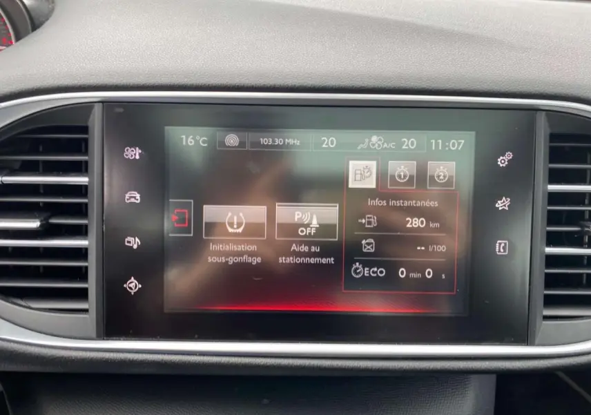 Écran tactile central du tableau de bord de la Peugeot 308 GTi 2016 affichant les aides à la conduite et la température intérieure.