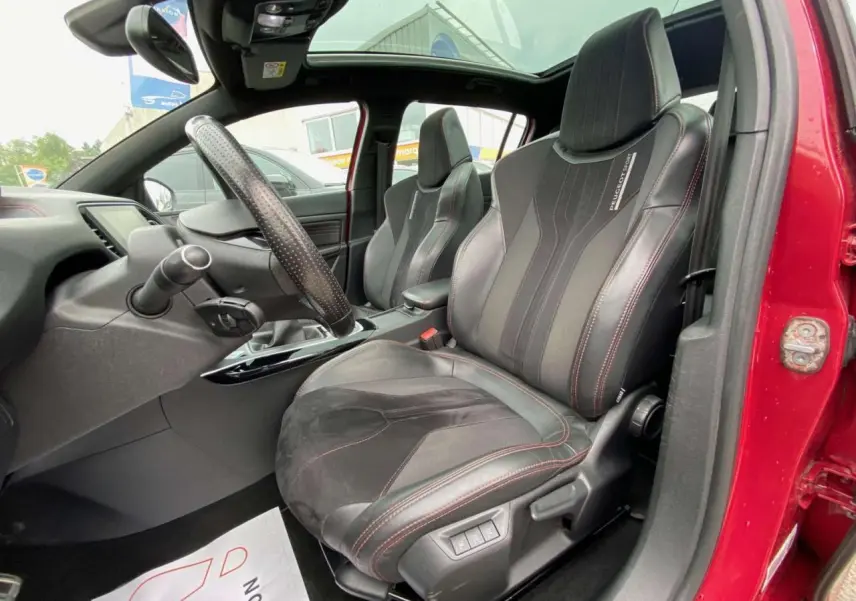 Intérieur avant droit de la Peugeot 308 GTi rouge 2016 avec sièges sport noirs et toit panoramique en verre.
