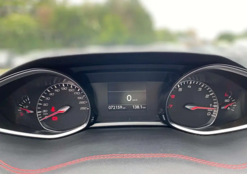 Gros plan sur le tableau de bord de la Peugeot 308 GTi 2016 avec compteurs analogiques et écran digital central.