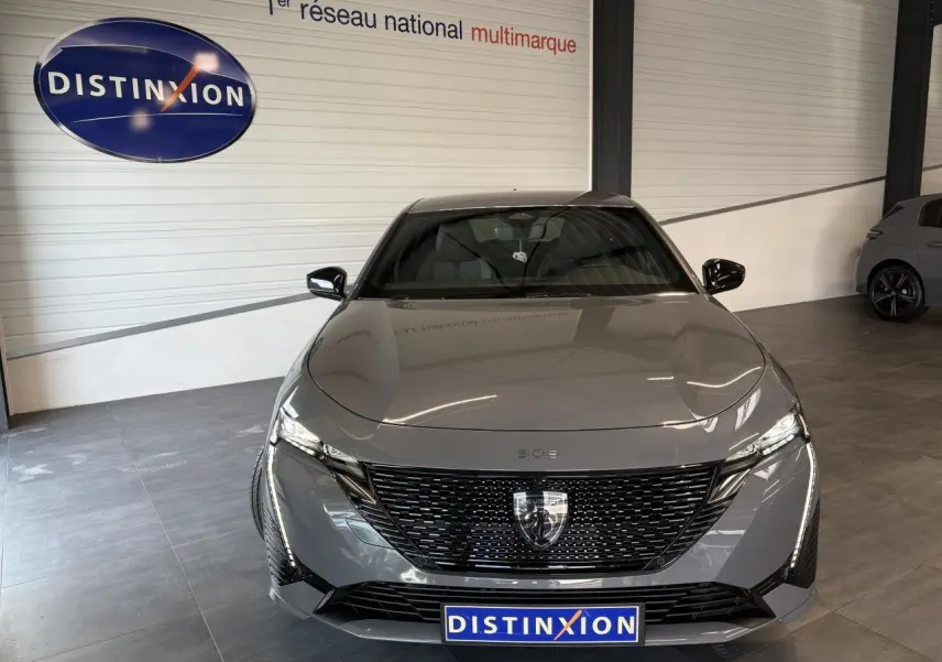 Vue de face d'une Peugeot 308 gris selenium avec calandre noire brillante et feux LED griffés dans un showroom