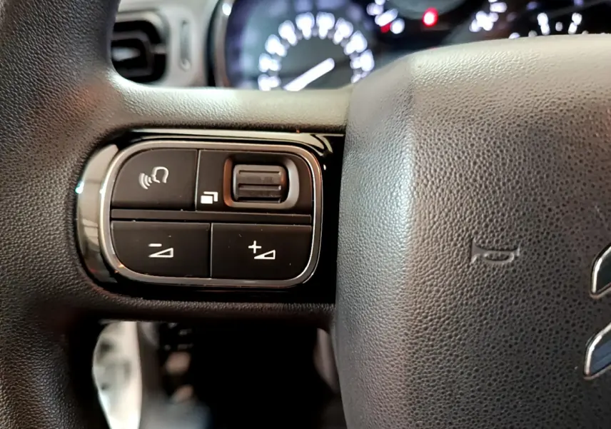 Gros plan sur les commandes à gauche du volant noir de la Citroën C3 PureTech 68 BVM Feel 2018.