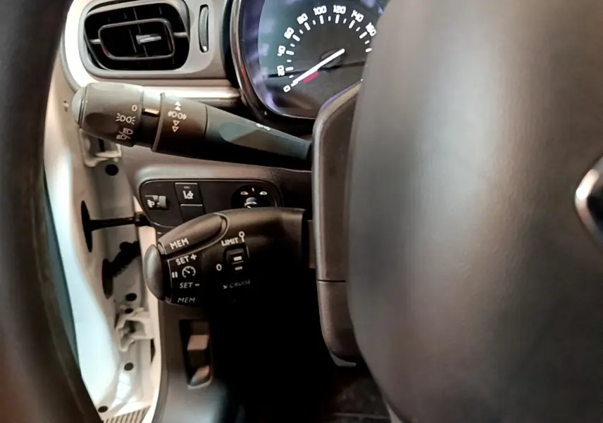 Vue rapprochée du volant et des commandes de régulateur de vitesse d'une Citroën C3 blanche de 2018.