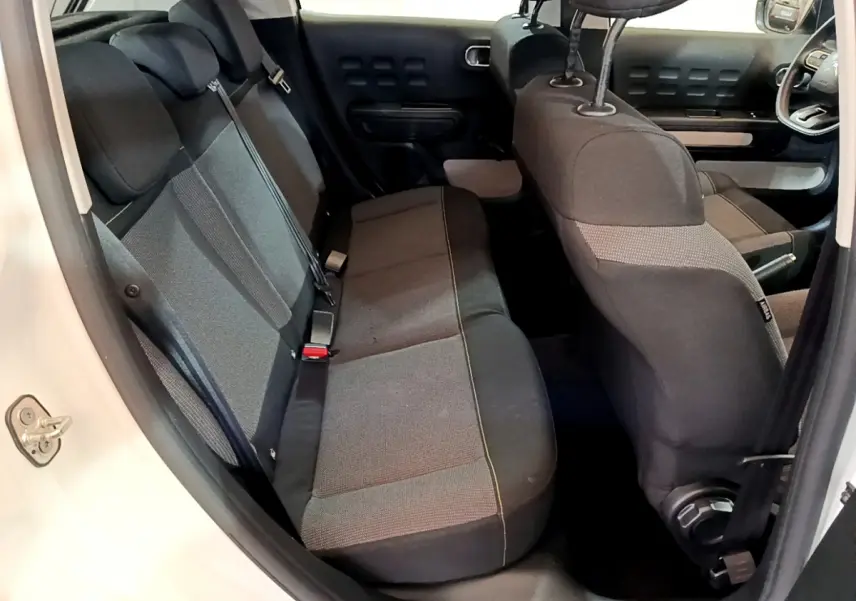 Vue intérieure côté gauche montrant la banquette arrière et l'avant de la Citroën C3 blanche avec sièges gris foncé.