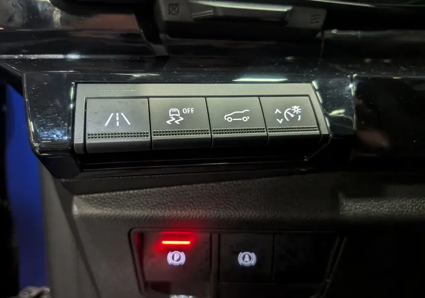Panneau de commandes avec boutons d'assistance et frein à main électronique allumé dans un Renault Austral E-Tech Hybrid 2024.