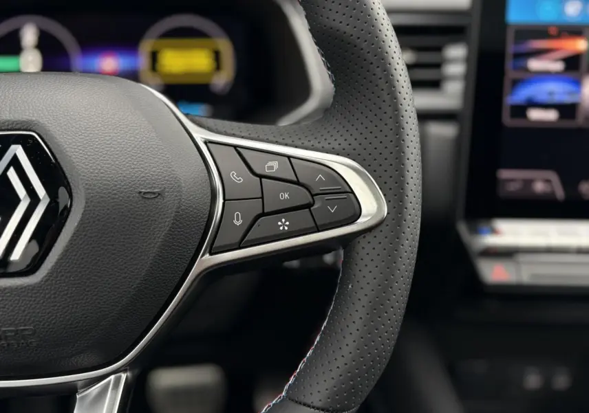 Gros plan sur le volant perforé avec commandes intégrées et logo Alpine sur Renault Captur hybride 2025.