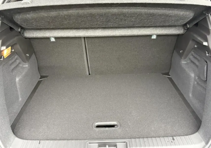 Coffre ouvert vu de face d’un Renault Captur blanc nacré avec intérieur de coffre gris foncé.