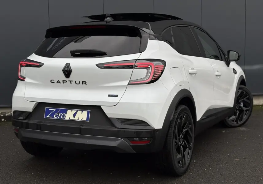 Vue 3/4 arrière droite du Renault Captur blanc nacré avec toit noir étoile et jantes noires distinctives.