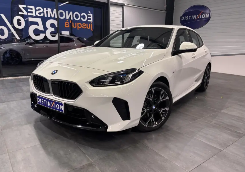 BMW Série 1 118D M Sport blanche vue 3/4 avant droit, avec calandre noire et jantes alliage 18 pouces bicolores.
