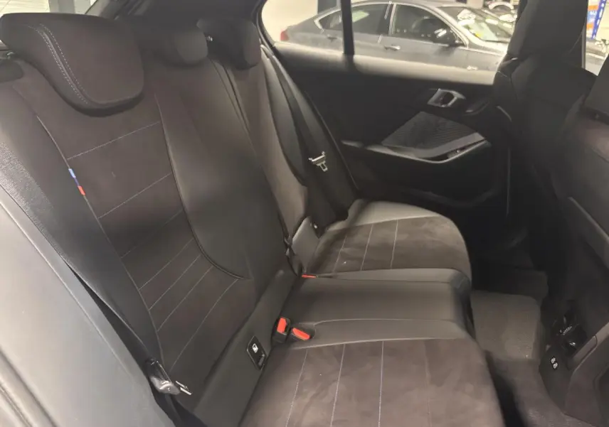 Vue intérieure côté droit des sièges arrière en Alcantara noir avec surpiqûres bleues de la BMW Série 1 118D M Sport 2025.