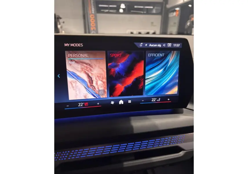 Écran central tactile affichant les modes de conduite Personal, Sport et Efficient dans une BMW Série 1 blanche.