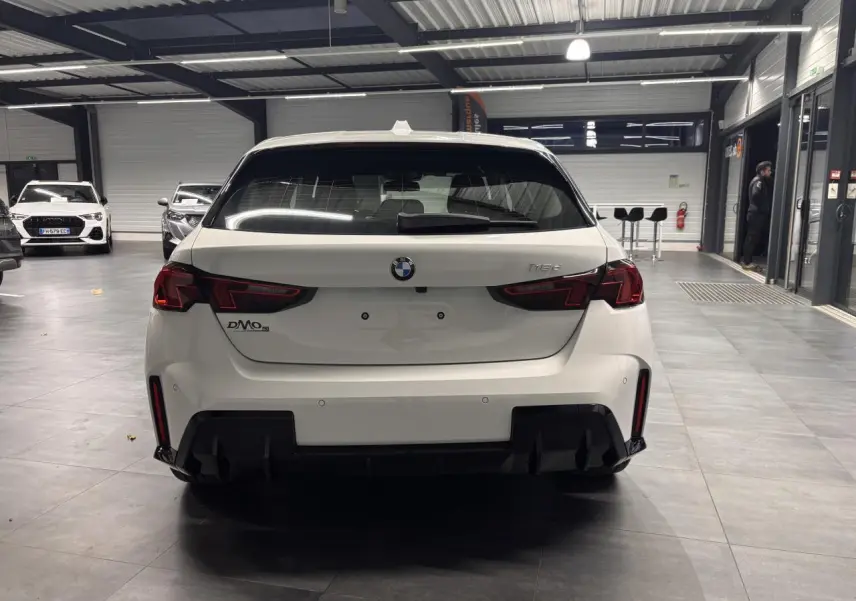 Vue arrière d'une BMW Série 1 blanche 118D M Sport 2025, avec diffuseur noir et feux LED distinctifs.