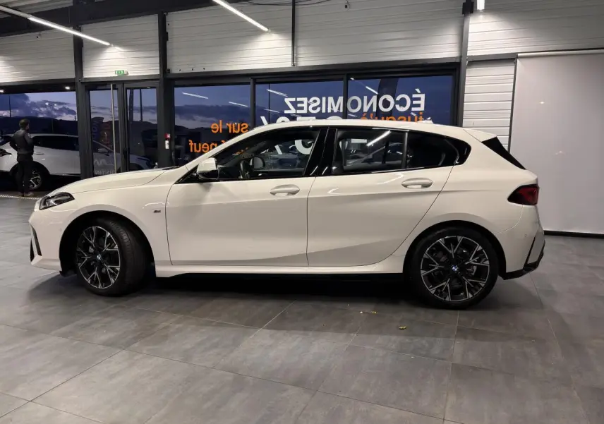 Vue de profil côté gauche d'une BMW Série 1 blanche 118D M Sport avec jantes alliage 18 pouces bicolores.
