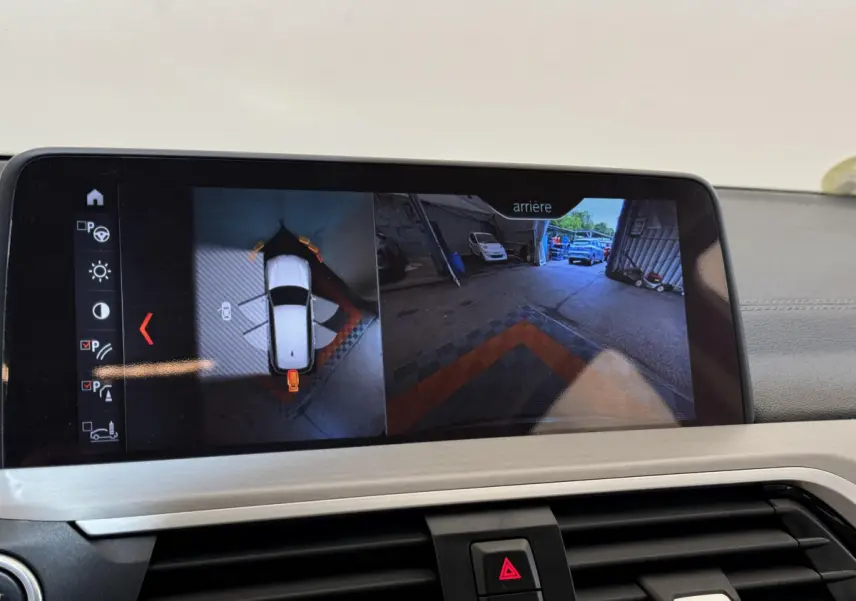 Écran tactile du système de navigation affichant la caméra de recul et vue 360° dans un BMW X3 gris foncé.