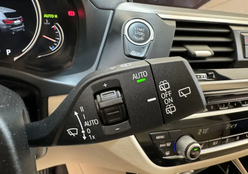 Gros plan sur la commande d’essuie-glace et bouton start/stop du tableau de bord beige d’un BMW X3 gris foncé 2018.