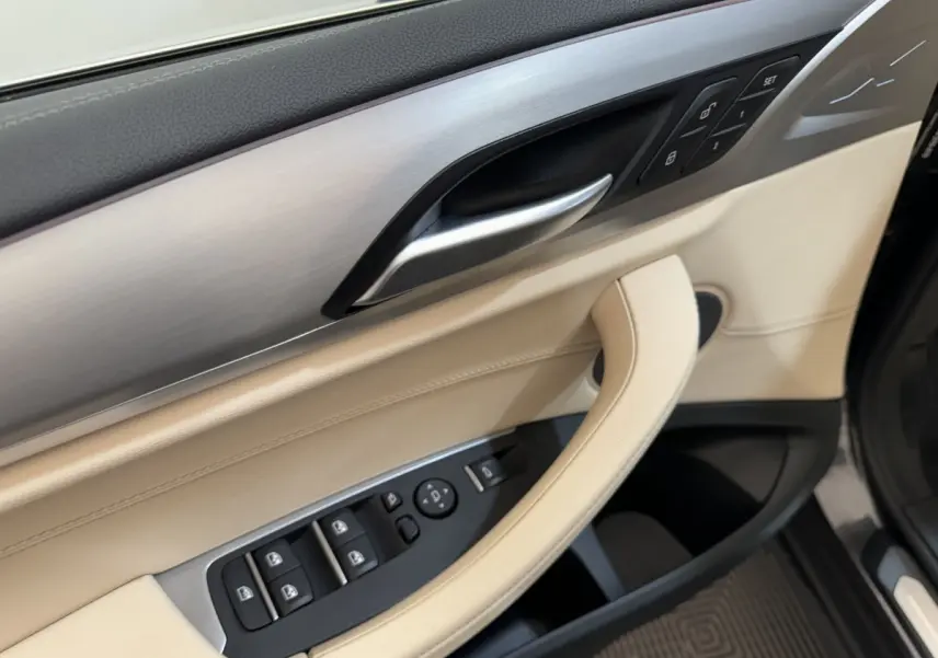Détail de la porte avant gauche beige et noire du BMW X3 xDrive30d 2018 avec commandes électriques et insert aluminium.
