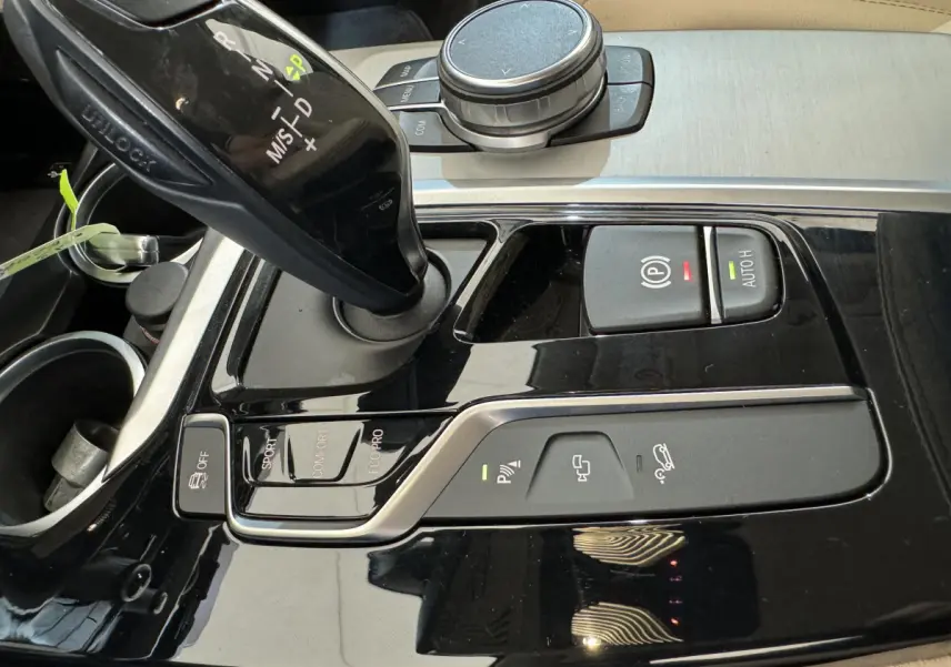 Gros plan sur la console centrale noire brillante du BMW X3 xDrive30d 2018 avec levier de vitesse automatique et boutons de contrôle.