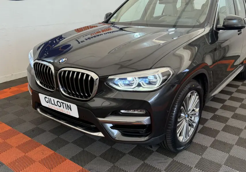 BMW X3 xDrive30d gris foncé vue 3/4 avant droit, avec phares LED allumés et calandre double haricot chromée.