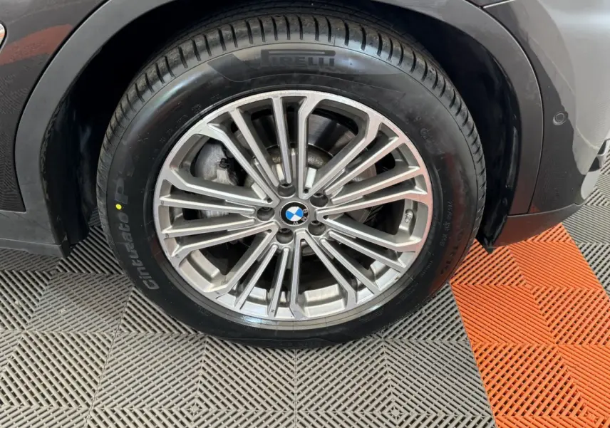 Gros plan sur la roue avant droite avec jante alliage argentée et pneu Pirelli sur BMW X3 gris foncé.