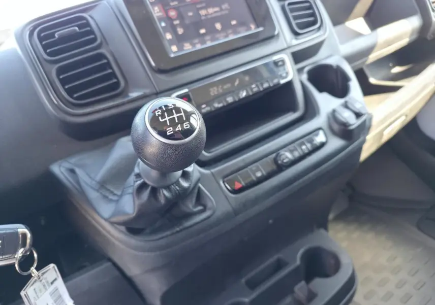 Gros plan sur le levier de vitesses manuel et la console centrale du Fiat Ducato Fourgon blanc, intérieur fonctionnel et moderne.