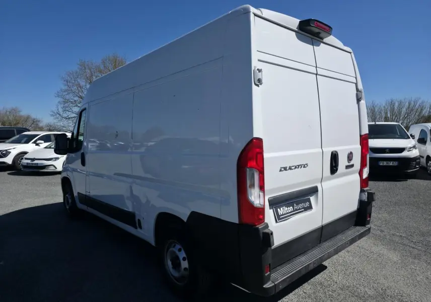 Vue 3/4 arrière droite d’un FIAT Ducato Fourgon blanc avec portes arrière tôlées et caméra de recul visible.