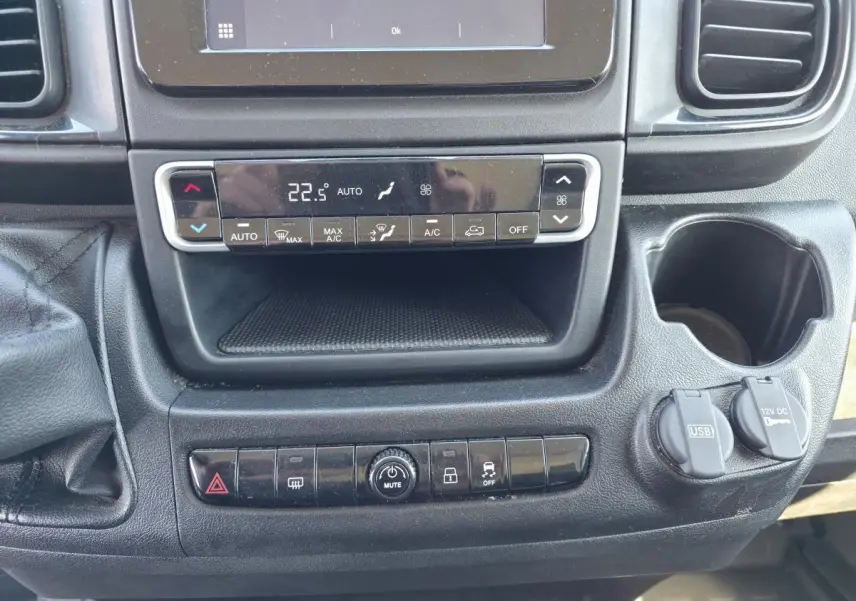 Vue rapprochée de la console centrale du Fiat Ducato Fourgon blanc 2023, avec commandes climatisation et ports USB visibles.