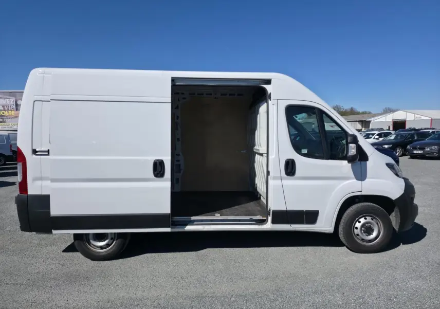 Fiat Ducato Fourgon blanc vu de profil droit avec porte latérale coulissante ouverte montrant l'intérieur vide.