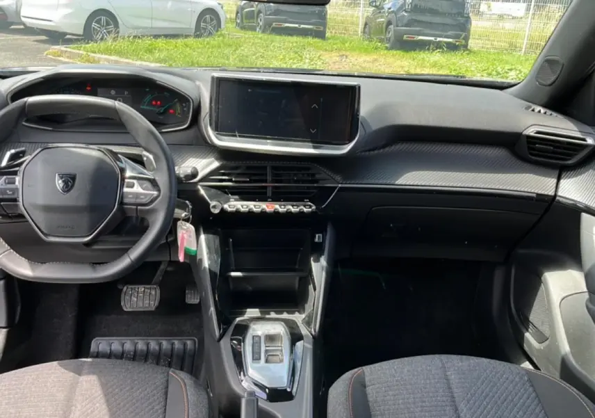 Intérieur Peugeot 2008 1.2 hybrid 2025 vu de face, tableau de bord noir avec écran tactile central et volant compact.