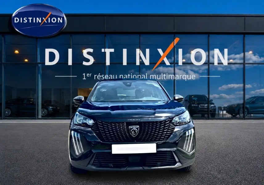 Vue frontale d'un Peugeot 2008 noir 2025 avec calandre distinctive et feux LED verticaux, devant une vitrine Distinxion.