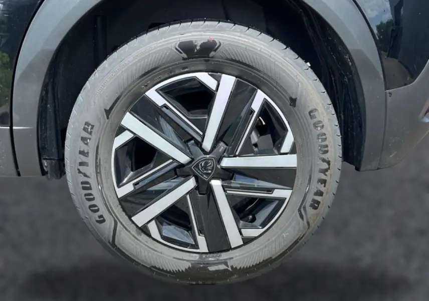Gros plan sur la roue avant gauche noire avec jante alliage bicolore du Peugeot 2008 1.2 hybrid 145 style e-dcs6 2025.