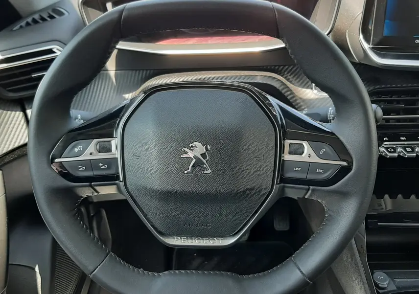 Volant noir de Peugeot 2008 2022 vue de face, avec commandes intégrées et tableau de bord partiellement visible.
