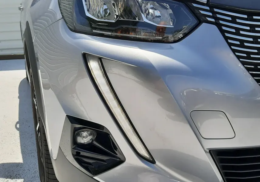 Gros plan sur l'avant droit gris Artense du Peugeot 2008 2022, mettant en valeur son phare LED et la calandre distinctive.