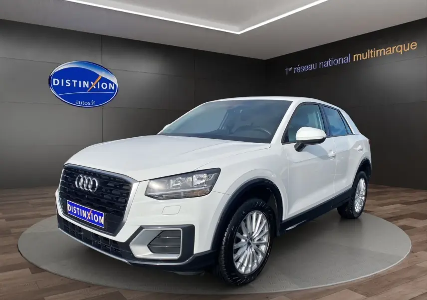 Audi Q2 blanc vue 3/4 avant droit en intérieur avec calandre noire et jantes argentées multibranches.