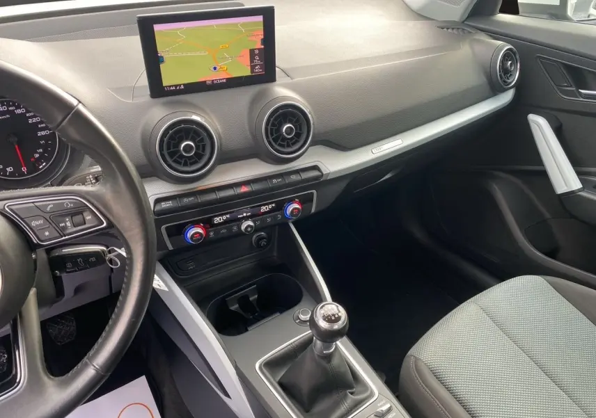 Intérieur noir et gris de l'Audi Q2 30 TDI 2019, vue côté conducteur avec écran GPS et boîte manuelle visible.