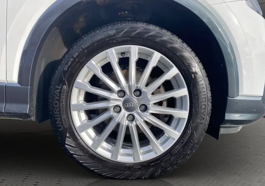 Gros plan sur la roue avant droite d'un Audi Q2 blanc de 2019 avec jante alliage argent et pneu Uniroyal.