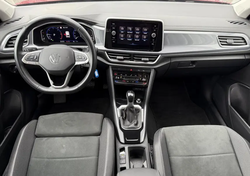 Vue intérieure du tableau de bord et volant cuir multifonction du Volkswagen T-Roc 2023 avec écran tactile central et sièges gris.