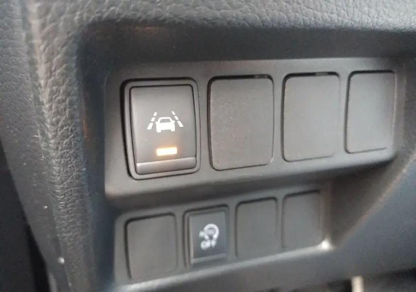 Gros plan sur les boutons de commande du tableau de bord du Nissan Qashqai noir 2019, avec témoin d'alerte de maintien de voie allumé.