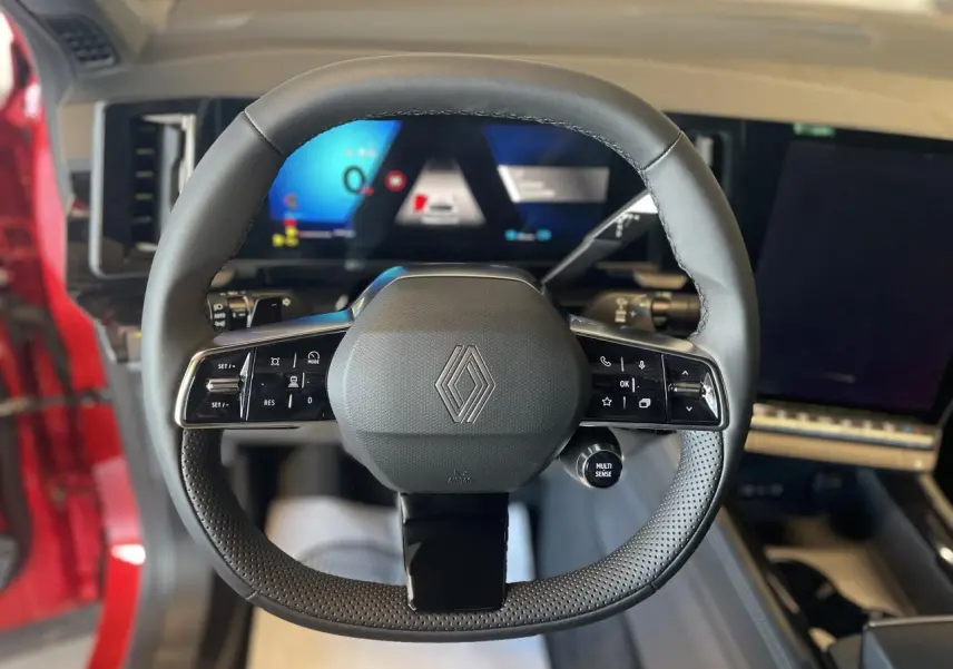 Vue frontale du volant Renault Rafale hybride 2025 avec commandes intégrées et tableau de bord numérique lumineux.