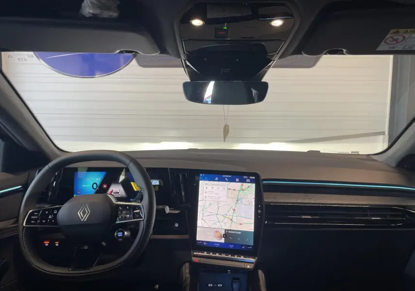 Vue intérieure frontale du tableau de bord noir du Renault Rafale 2025 avec écran tactile central affichant la navigation.