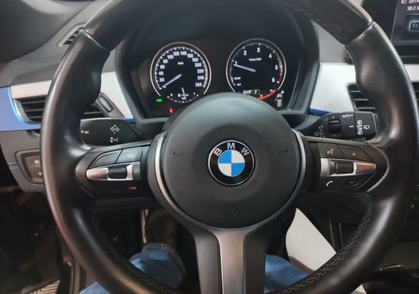 Vue rapprochée du volant cuir noir de la BMW X1 xDrive20d 2022 avec tableau de bord et commandes intégrées visibles.