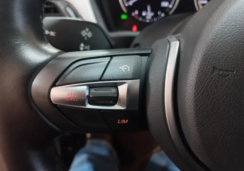 Gros plan sur les commandes du régulateur de vitesse au volant cuir noir de la BMW X1 xDrive20d M Sport 2022.