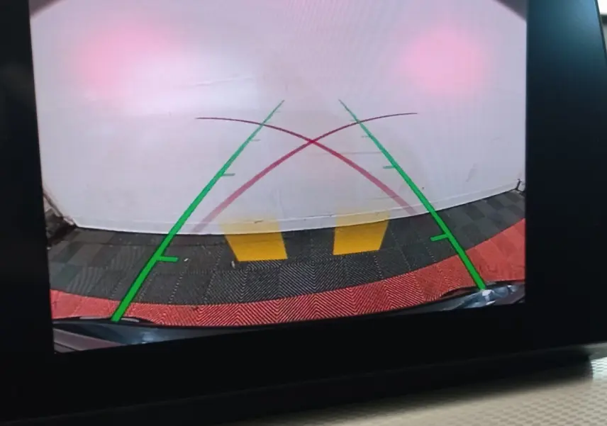 Vue caméra de recul du BMW X1 noir xDrive20d M Sport 2022, avec lignes de guidage vertes et rouges sur sol coloré.