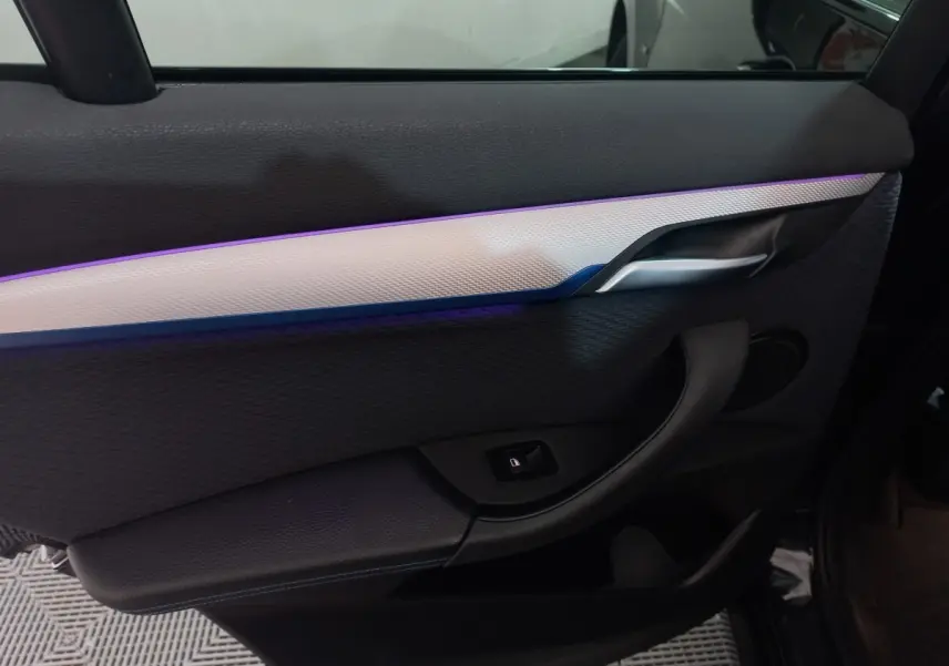 Gros plan sur la porte intérieure côté gauche noire du BMW X1 xDrive20d M Sport 2022 avec éclairage d'ambiance violet.