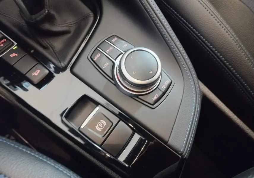 Gros plan sur la molette de commande et frein à main électrique dans l’habitacle noir de la BMW X1 xDrive20d M Sport.