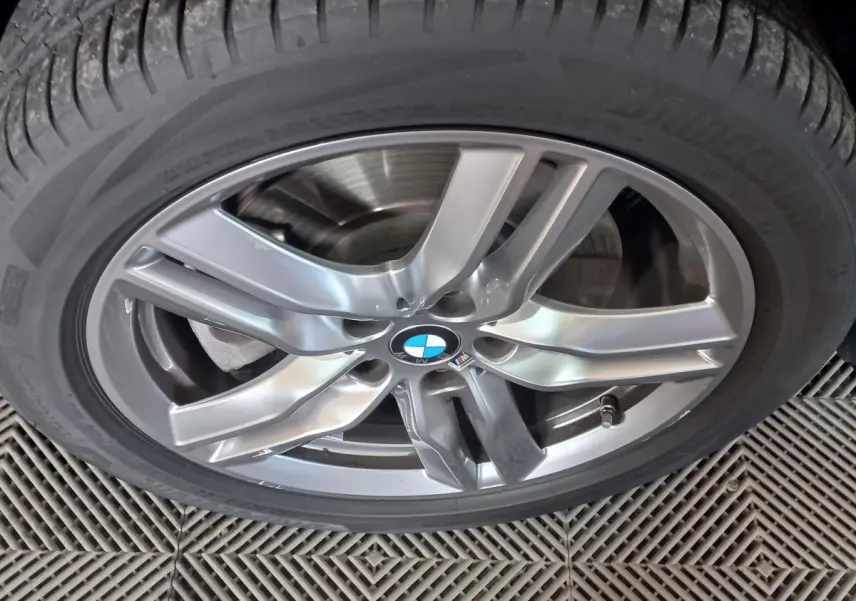 Gros plan sur la jante alliage argentée avec logo BMW d’un BMW X1 noir, vue centrée sur la roue.