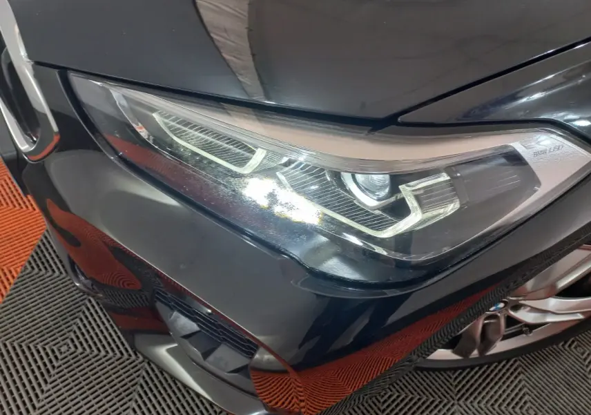 Gros plan sur le phare avant droit d’un BMW X1 noir, mettant en valeur les lignes LED distinctives et la calandre M Sport.