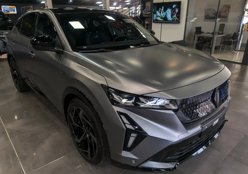 Vue 3/4 avant gauche d’un Renault Rafale gris schiste satin avec jantes noires et calandre distinctive en showroom.