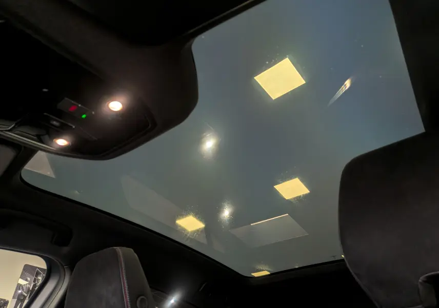 Vue intérieure du toit panoramique du Renault Rafale gris Schiste Satin, mettant en valeur l'éclairage intérieur et les sièges noirs.