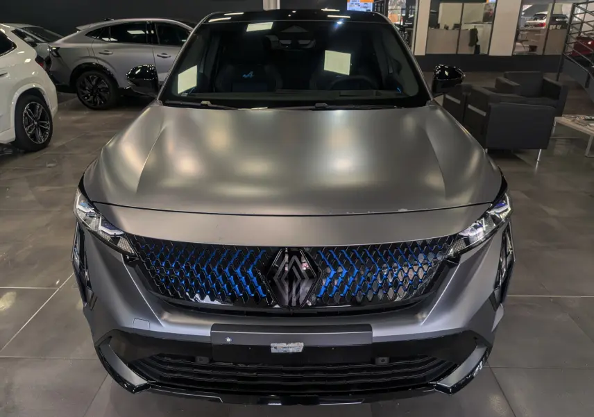 Vue frontale du Renault Rafale gris schiste satin avec calandre noire à motifs bleus et logo central distinctif.