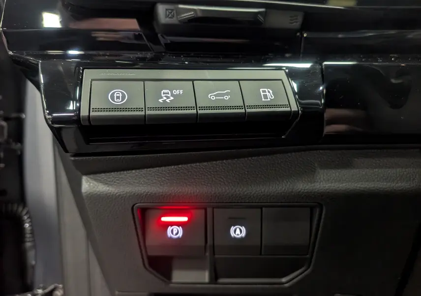 Gros plan sur les commandes intérieures noires du tableau de bord du Renault Rafale hybride, avec voyants lumineux rouges et blancs.